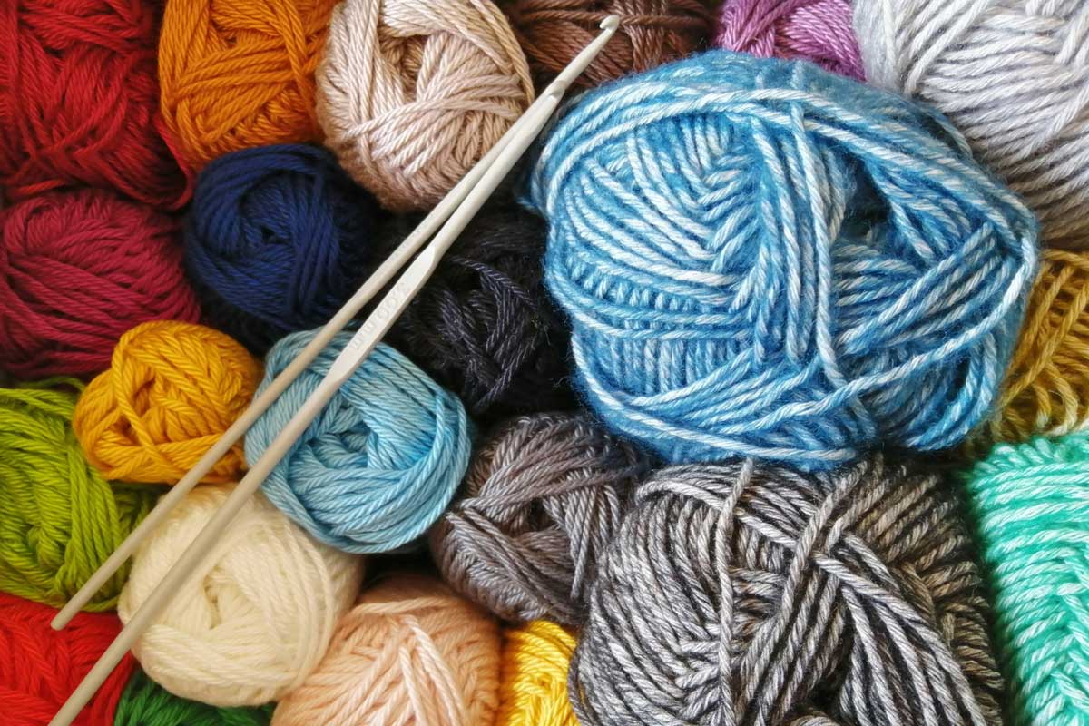 Pelotes de laine de toutes les couleurs et une paire de crochets