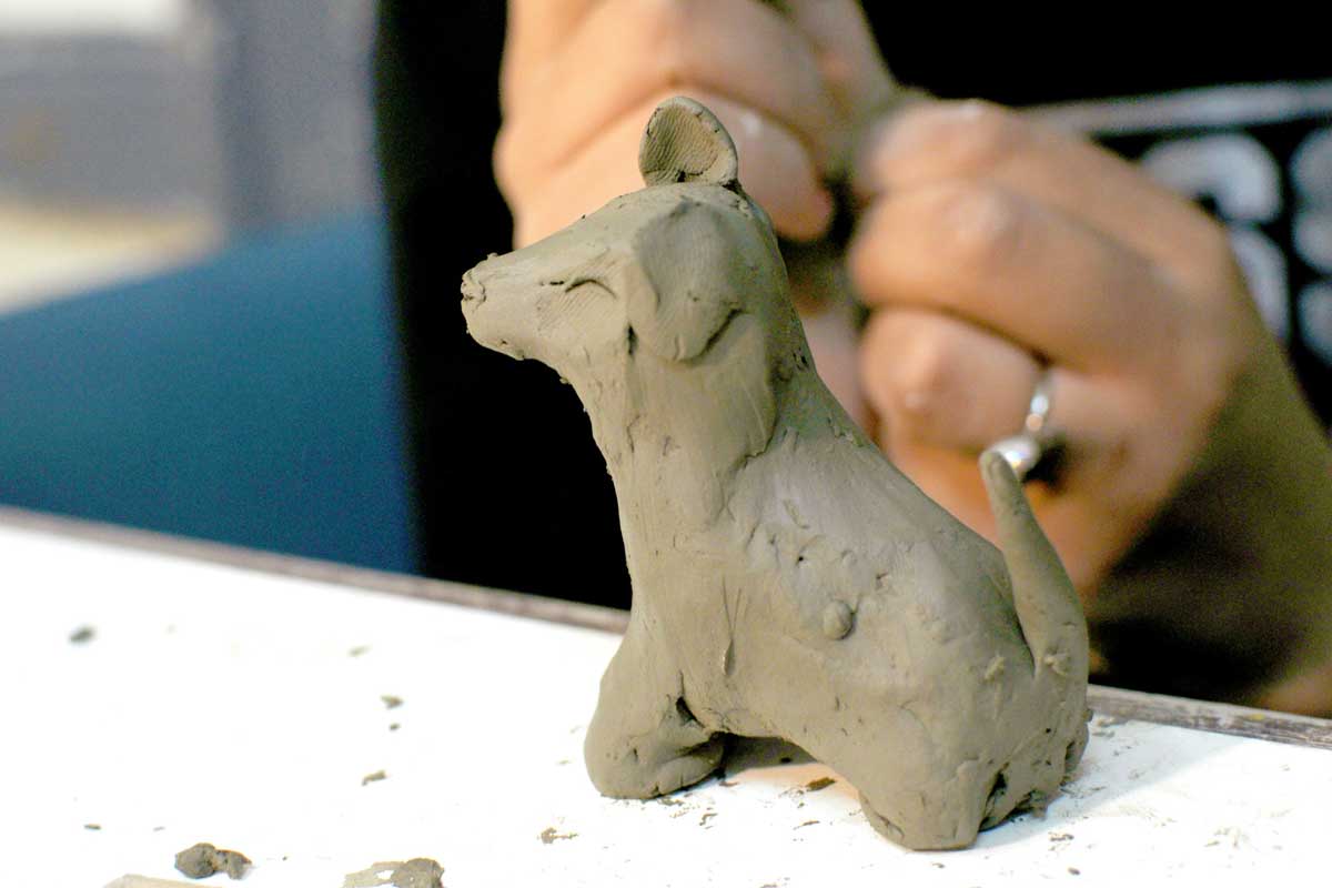 Une personne crée un petit chien en terre