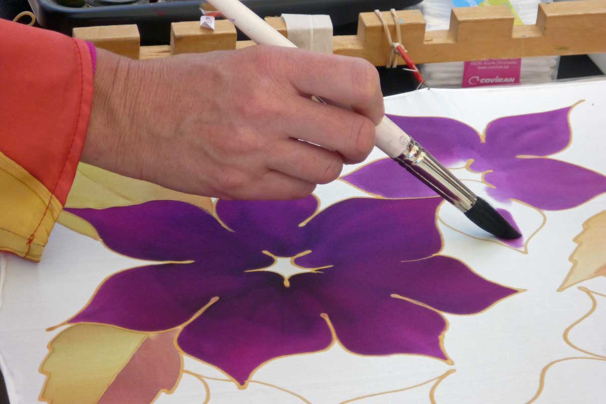 Peintre sur soie en train de peindre une fleur violette