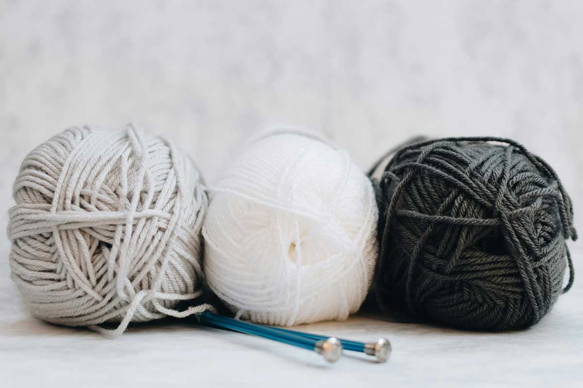 3 pelotes de laine et deux aiguilles à tricoter
